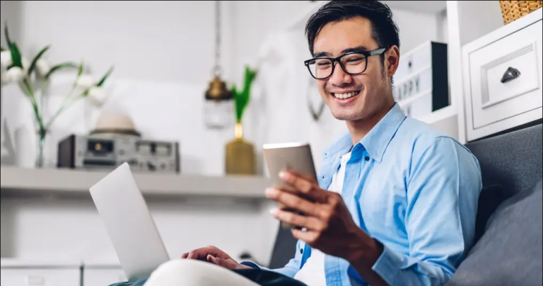 man looking at leads on phone and laptop