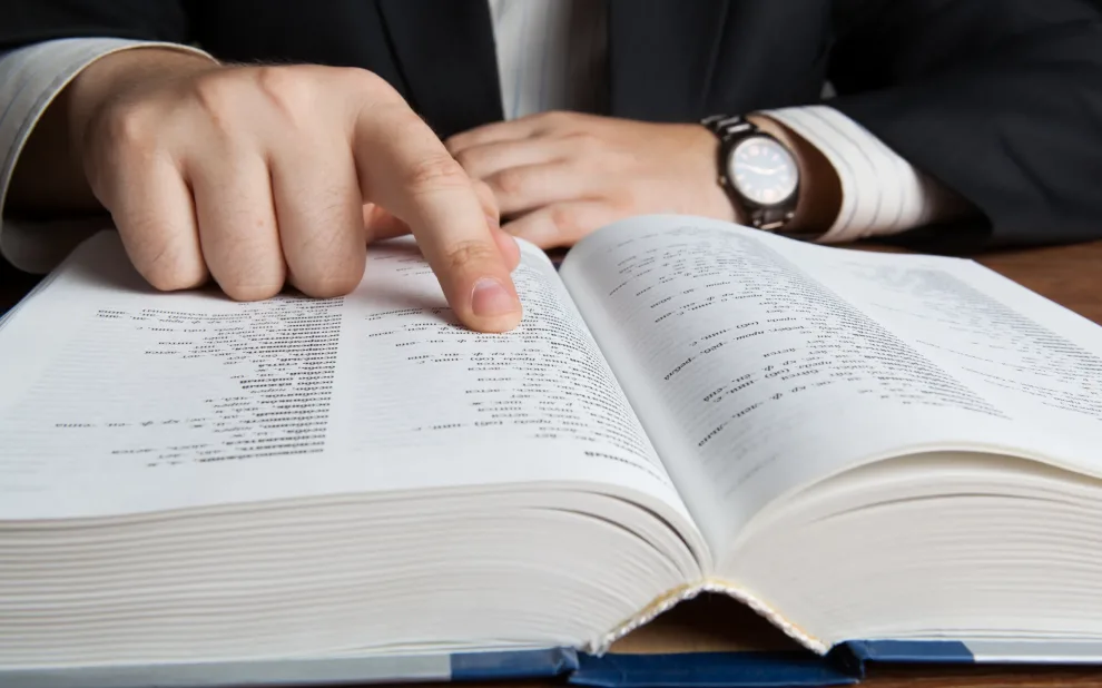 man looking in the large dictionary man in suit pointing at text book