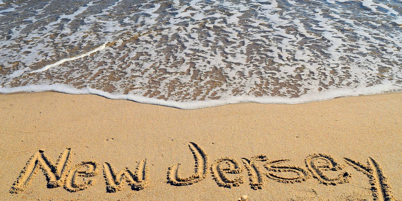 nj-solar-leads beach with new jersey written in sand